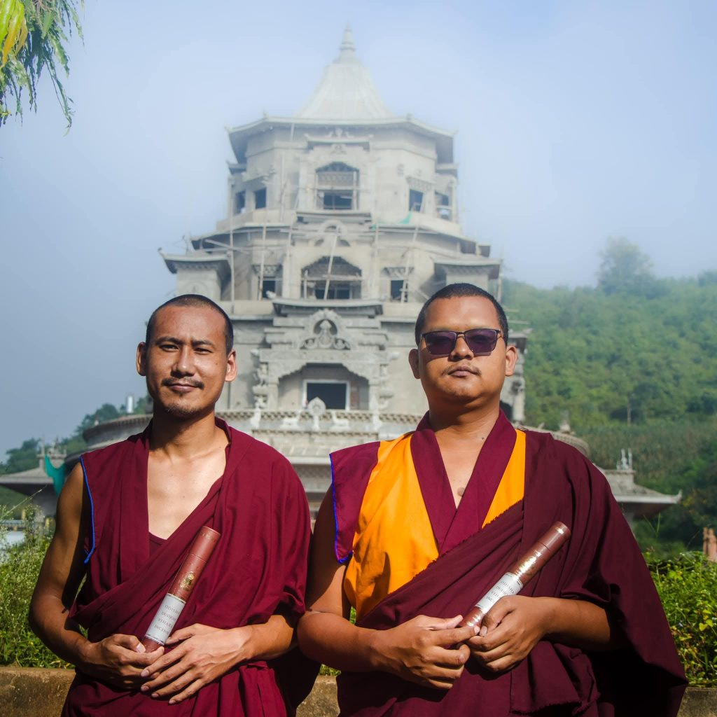 Two monks of Dudjom Dundul Raptenling Monastery holding incense tubes in front of the Zangdok Palri temple