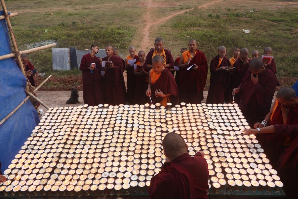 Monks lighting rows of butter lamps at Dudjom Dundul Raptenling Monastery